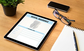 Dental insurance form on tablet next to office supplies