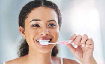 Closeup of woman smiling while brushing her teeth