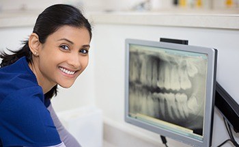 Dental assistant looking at x-rays on computer