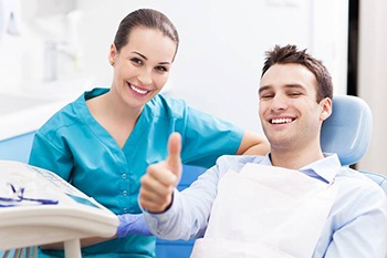 smiling man in dental chair giving thumbs up