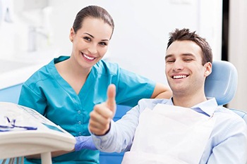 Smiling man in dental chair giving thumbs up