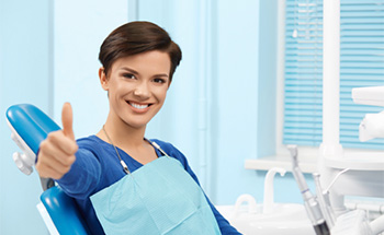 Smiling woman in dental chair giving thumbs up