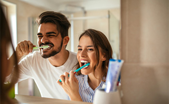 Man and woman brushing teeth together