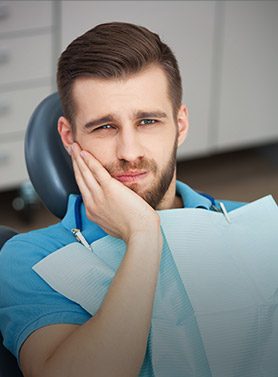 Man in dental chair holding jaw