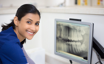 A dentist looking at a dental X-ray on a computer screen 