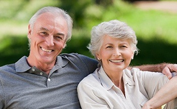 Senior man and woman smiling outdoors with dental crowns and bridges in Woodstock