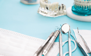 Several dental instruments and models of teeth on desk