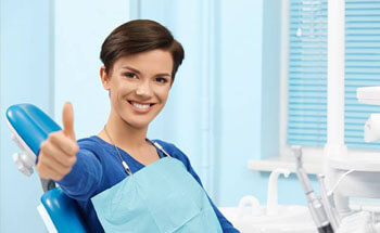 Woman in dental chair giving thumbs up