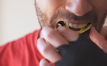 Man placing yellow mouthguard over teeth