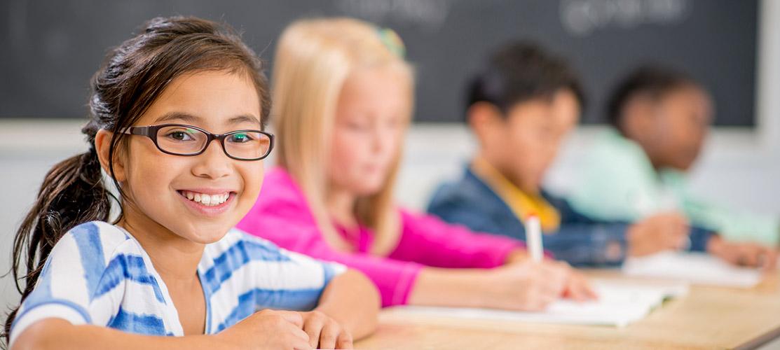 Smiling child sitting at desk in classroom