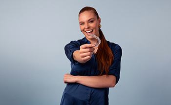 Woman holding her aligners and smiling