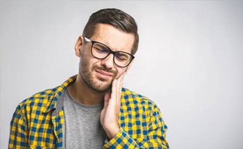 Man holding his cheek in pain before root canal treatment in Woodstock