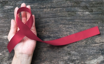 Hand holding a maroon ribbon representing oral cancer