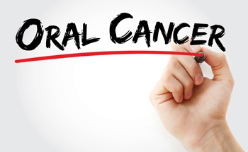 Hand writing the words oral cancer screening on board”
