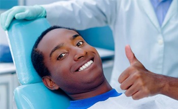 Man with thumb’s up in dentist’s chair