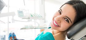 Smiling woman in dental chair receiving dental services in Woodstock