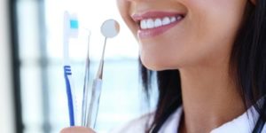 Smiling woman holding a toothbrush and dental instruments