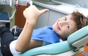 A child giving a thumbs-up at his dental appointment.