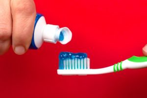 person squeezing toothpaste on a toothbrush