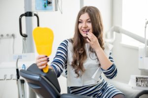 Female patient in dentist’s chair looking in yellow mirror