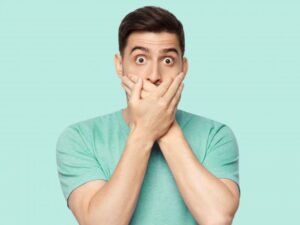 Man covering his mouth after breaking a tooth