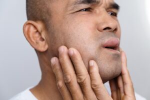Man holding his swollen face with hands.